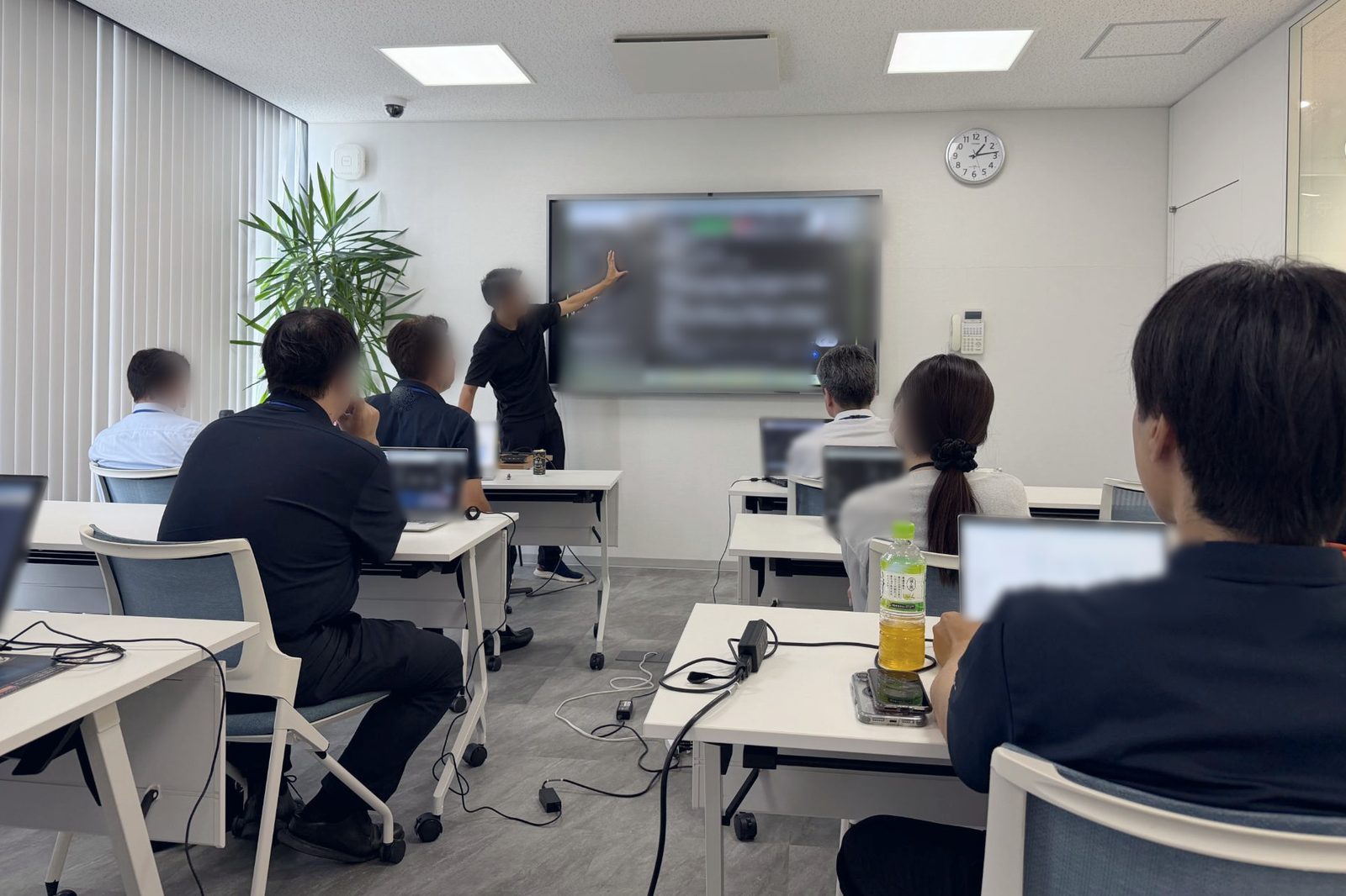 講師が前の大きな画面を指して説明し、受講者がそれぞれのパソコンを開いて聞いている研修の様子